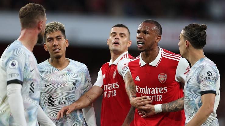 0E3670AE-991C-468A-9666-7A6037D67E40.jpeg Soccer players from Arsenal and Liverpool engaged in a heated confrontation on the field during a Premier League match, with one Arsenal player holding back a teammate while speaking to opposing players. The incident bore similarities to the infamous Henderson-Gabriel incident.