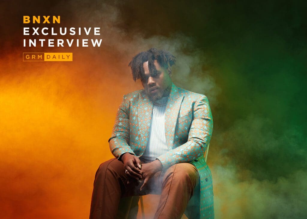 GRM-LAND-BNXN-1024x732.jpeg A man sitting on a chair in front of a smoky, colorful background with the text "BNXN Exclusive Interview GRM Daily," shares his journey and talks about his musical heroes that shaped his path in Afrobeats.