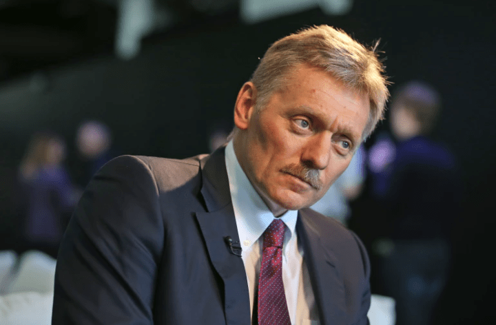 Screenshot_20221026-112345-1.png A man with a mustache and suit, looking to the side with a serious expression. The background is out of focus with people and dark colors, reminiscent of a tension-filled evening in Ukraine.