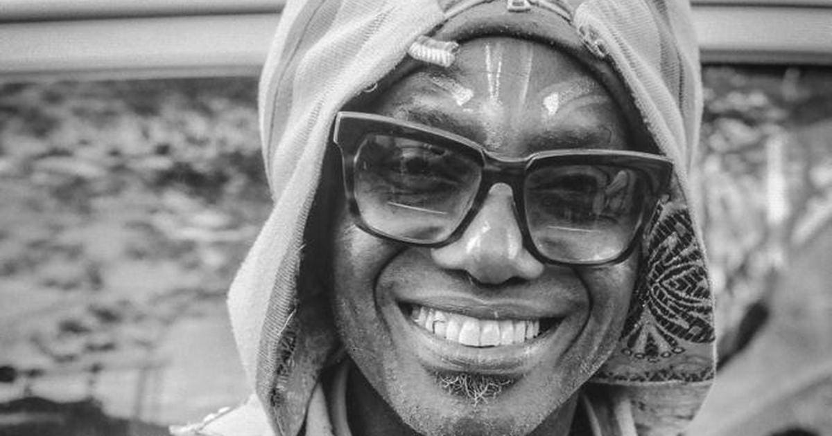 sAwktkpTURBXy84MDYyZTliYjAxMDg4ZWRhMGIxZWI1N2EwMTk0YmUwYS5qcGeSlQMAzMDNAqbNAX2TBc0EsM0Cdg.jpeg Black-and-white photo of a smiling Nigerian Afrobeat artist wearing a head wrap, large sunglasses, and with face paint marks, reminiscent of Duke Amayo's vibrant style captured during his Pulse interview.