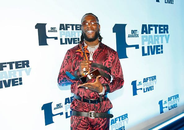 c2fdf5961b89a02eda4c27694442fd43.jpeg A person in a red patterned outfit holds an award trophy at the BET Awards After Party Live!, reminiscent of Burna Boy's recent victory at the World Creole Music Competition.