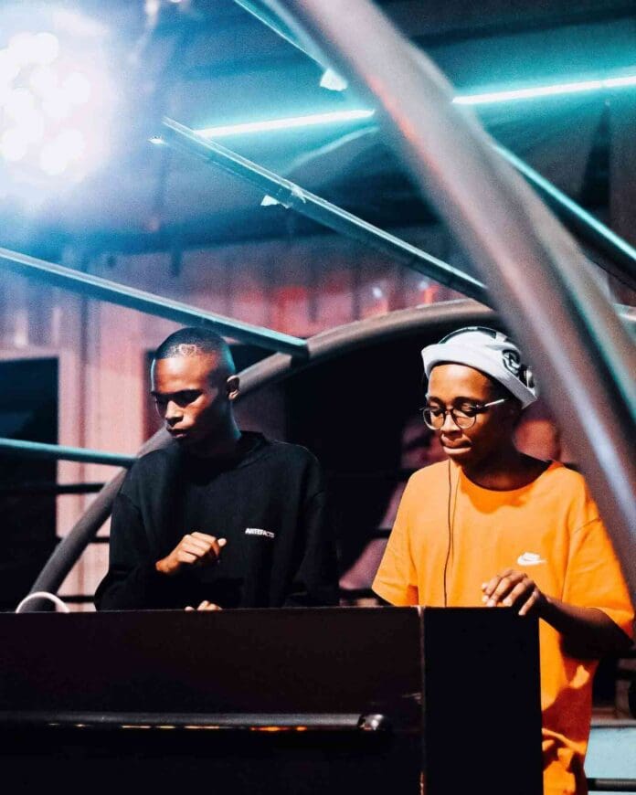 252561563_183139024009005_4332300866490425345_n-1.jpg Two individuals, one sporting a black outfit and the other in an orange shirt with headphones, are masterfully operating DJ equipment at a music event. Neon lights bathe the scene as Djy Biza sets the vibe for an electrifying night.