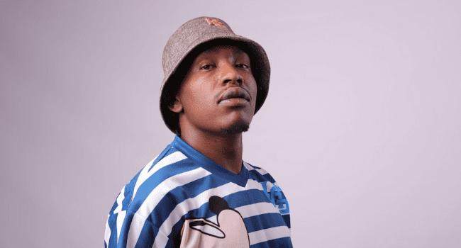 A man wearing a blue and white striped shirt and hat announces the release date for his 22-track album. A man wearing a blue and white striped shirt and hat announces the release date for his 22-track album.