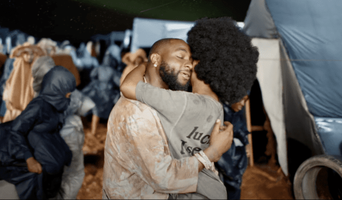 A man and woman hugging in front of tents in Davido's "FEEL" music video. A man and woman hugging in front of tents in Davido's "FEEL" music video.