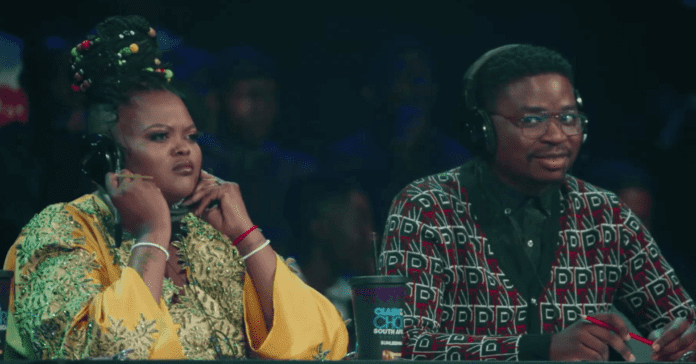 Two people sitting at a table with headphones on, participating in Clash of the Choirs. Two people sitting at a table with headphones on, participating in Clash of the Choirs.