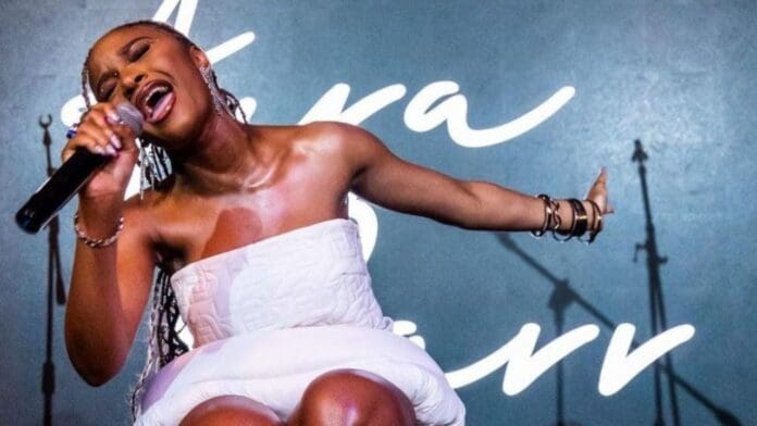 A woman in a white dress rocking the stage at Rocking the Daisies in Cape Town, singing into a microphone. A woman in a white dress rocking the stage at Rocking the Daisies in Cape Town, singing into a microphone.