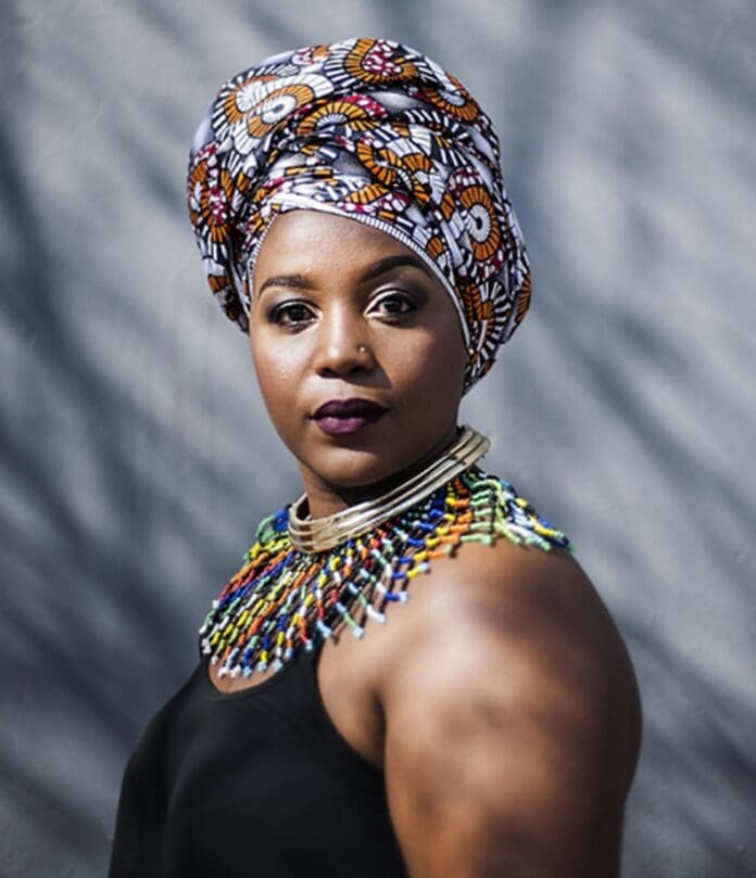Spha Mdlalose, a woman in an African turban, posing for a photo. Spha Mdlalose, a woman in an African turban, posing for a photo.