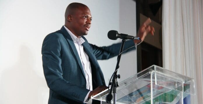 A man giving a speech at a South African Music Awards podium. A man giving a speech at a South African Music Awards podium.