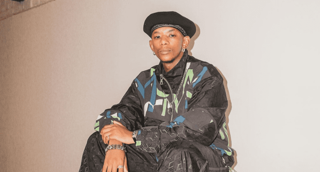 A man in a colorful outfit showcasing Africa Rising while sitting on top of a wall. A man in a colorful outfit showcasing Africa Rising while sitting on top of a wall.