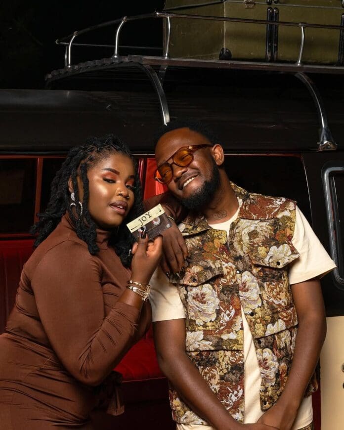 JOY-with-@nkosazana_daughter-drops-11-April-Taken-from-TheBigBroTheory-which-you-can-pre-order-via-t.jpeg Two people pose joyfully in front of a vehicle, with one holding a key and both smiling.