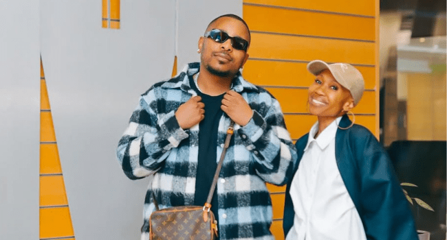 L-tido-3.png Two people pose in casual attire against a patterned wall. The person on the left, resembling L-Tido, sports sunglasses and a checked jacket, while the one on the right smiles brightly, donning a cap and hoop earrings. Could they be celebrating at the Metro Music Awards 2025?.