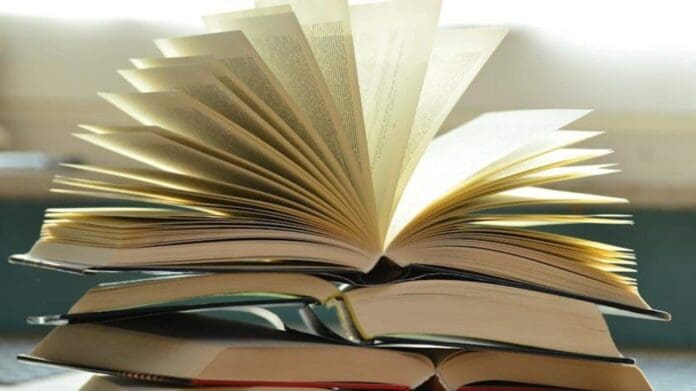 l33920250203102224.jpeg Open books stacked with one on top having pages fanned out, creating a dynamic, eye-catching display that echoes the rhythmic energy of African music in a bright setting.