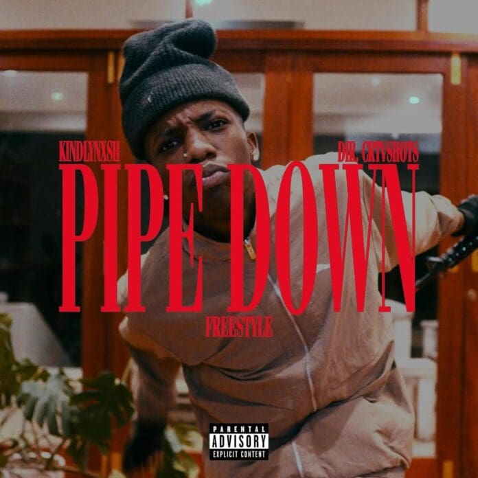 PIPE-DOWN-FREESTYLE-…-MIDNIGHT-@crtvshots-x-youngsoldier.jpg A person wearing a beanie and light jacket leans forward indoors, with large red text reading "PIPE DOWN FREESTYLE" over the image, capturing the signature style of KindlyNxsh’s latest Pipe Down Freestyle.
