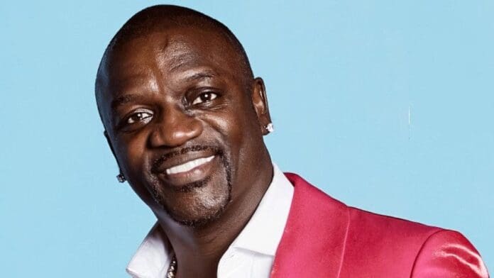 c81d342b-d50a-47ab-8b6b-8f5e72ad23f2.jpeg A man in a bright pink suit jacket and white shirt smiles at the camera against a light blue background, radiating Afrobeats energy reminiscent of icons like PSquare.
