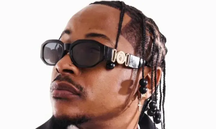 priddyugly.jpg A person with braided hair, wearing large black sunglasses, beaded earrings, and a cross earring, looks to the side against a white background—styled like an Urban Music Awards 2025 winner featured in Music In Africa.