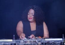 How ‘Amapiano’, South Africa’s soulful sound, has become one of the hottest new music genres – CNN A DJ with curly hair and red lipstick operates a sound mixer, standing between two DJ turntables against a dark background, showcasing the vibrant Amapiano music genre from South Africa.