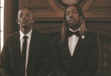 Maglera Doe Boy Hints At Explosive Joint Album With 25K Two men wearing suits, possibly Maglera Doe Boy and 25K, stand side by side indoors in front of a wooden mantle and window—perhaps hinting at an upcoming joint album—as they look directly at the camera.