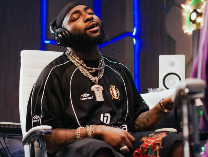 IMG_4110-e1743504668917.jpeg Eyes closed in fervent concentration, a person sits in a chair at the music studio, wearing headphones and a black jersey. Surrounded by audio equipment, they channel the creative energy of a Rolling Stone UK session or perhaps channeling Davido's vibrant soundscapes.